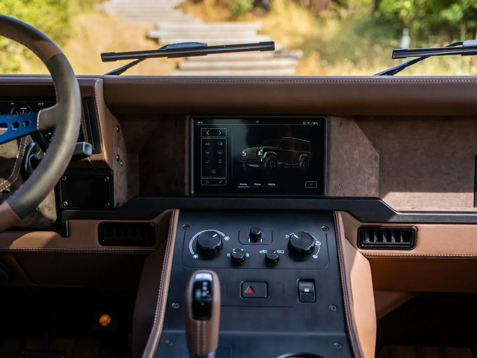 The central touchscreen in Hippo’s brown dashboard, showing a vehicle view and control sidebar above physical controls.